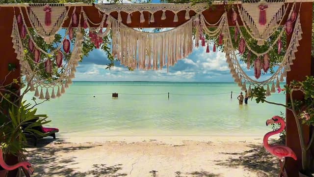 Macramé arch facing the turquoise sea at Punta Coco, with decorative pink flamingos