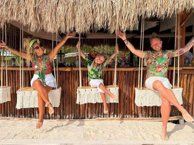 A family laughing on the swings under the bar's palapa